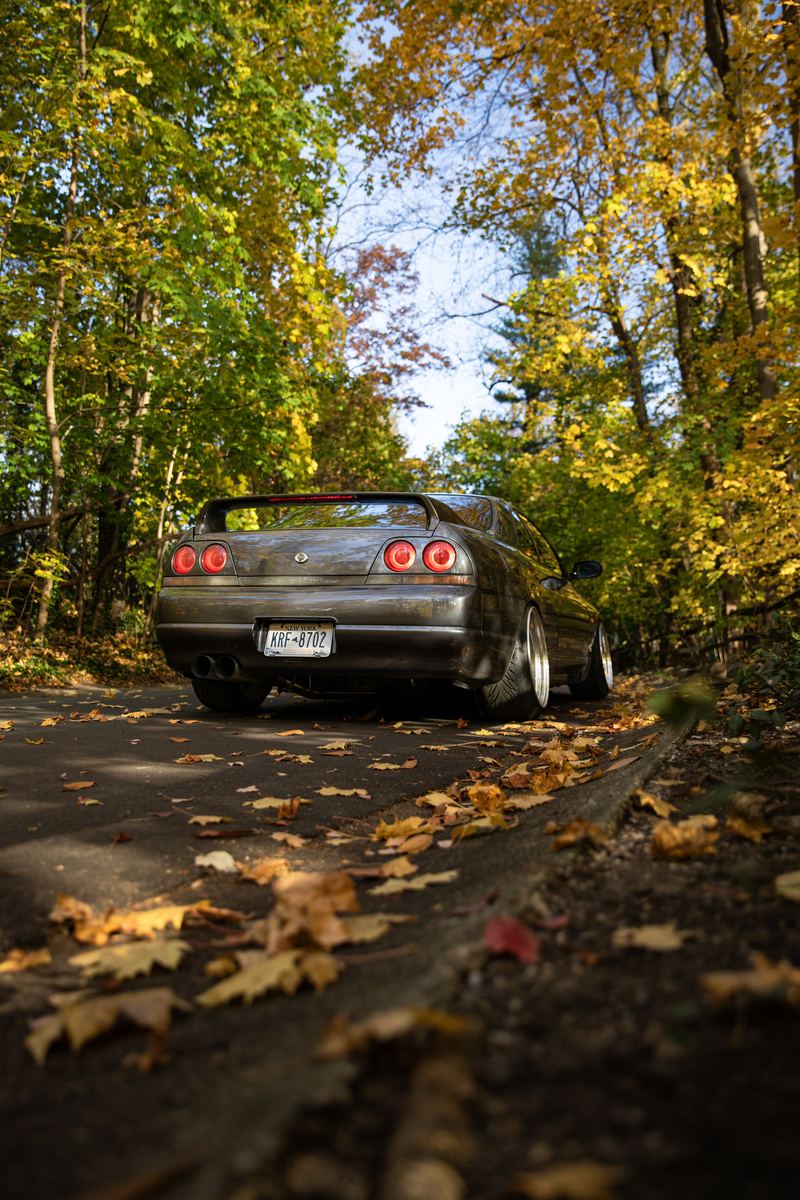 Nissan Skyline R33 on an autumn leaf-covered road
