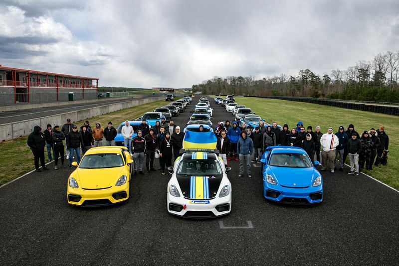 Track day drivers and cars lined up on the front straight