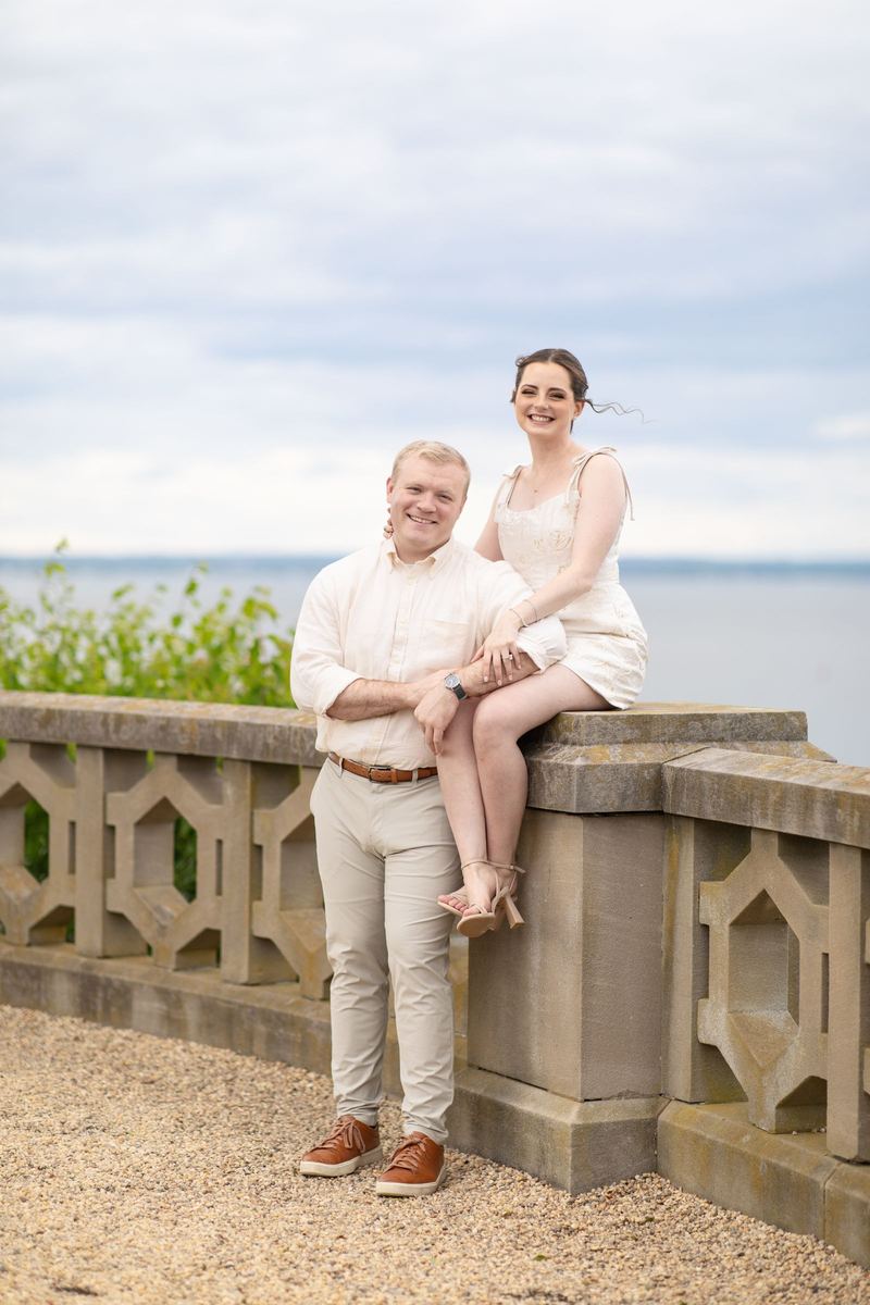 Couple posed on a stone balustrade above the water