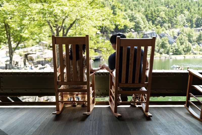 Couple holding hands between rocking chairs overlooking a lake