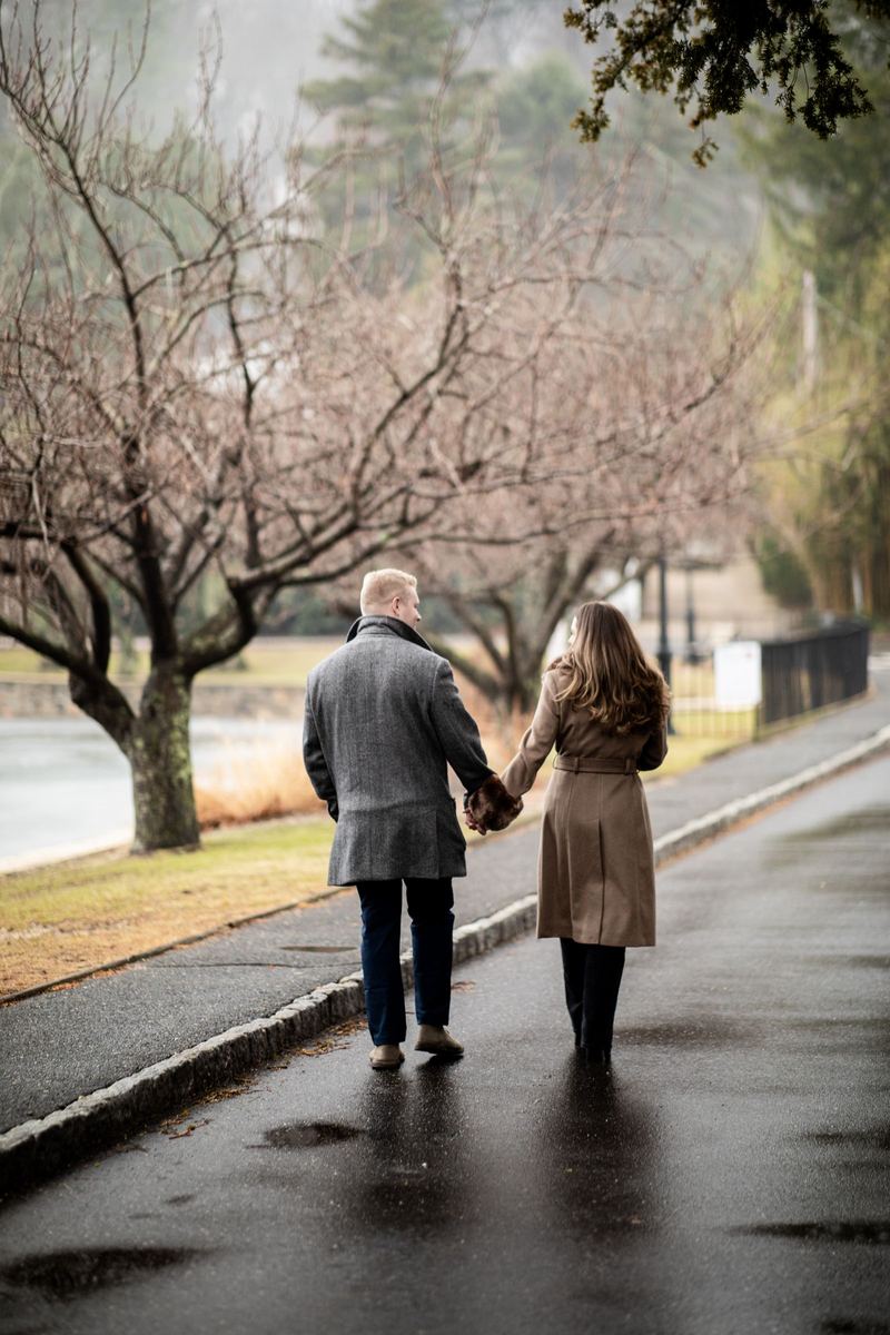 Couple walking hand in hand down a rain-soaked lane
